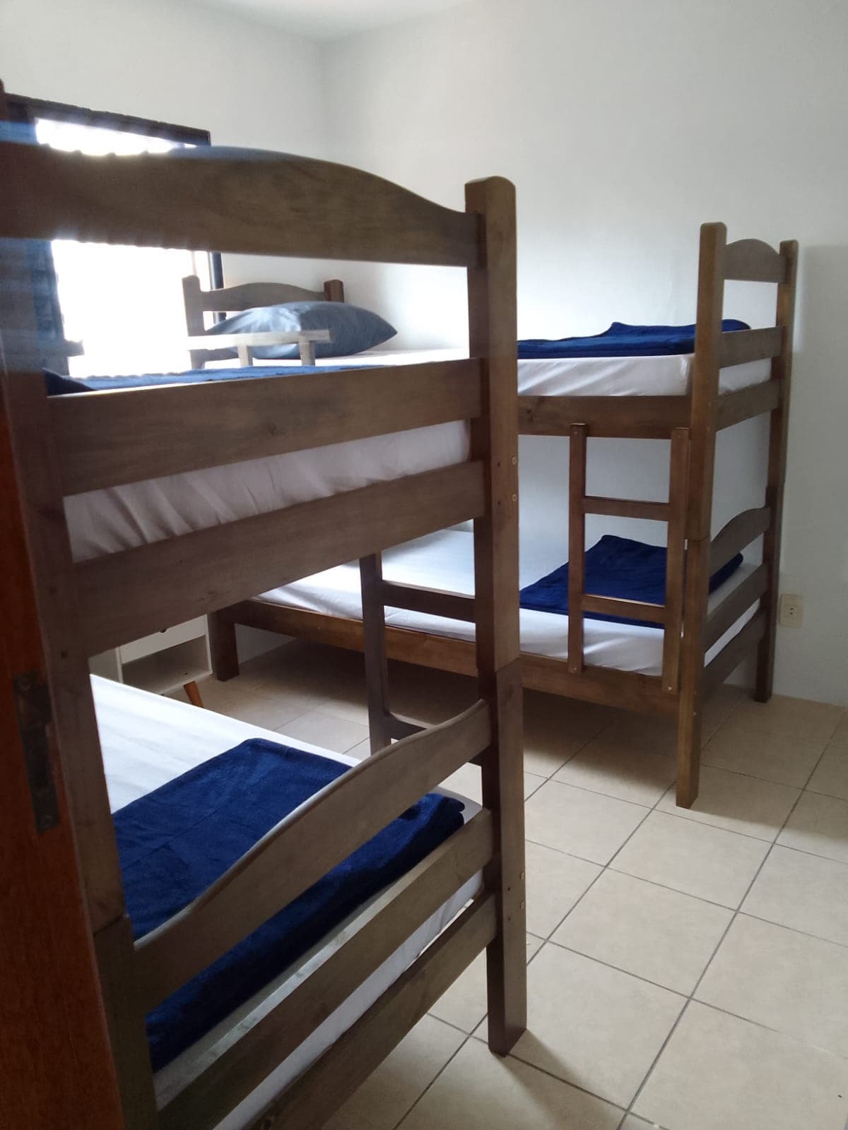 Quarto coletivo com camas e ventilação natural